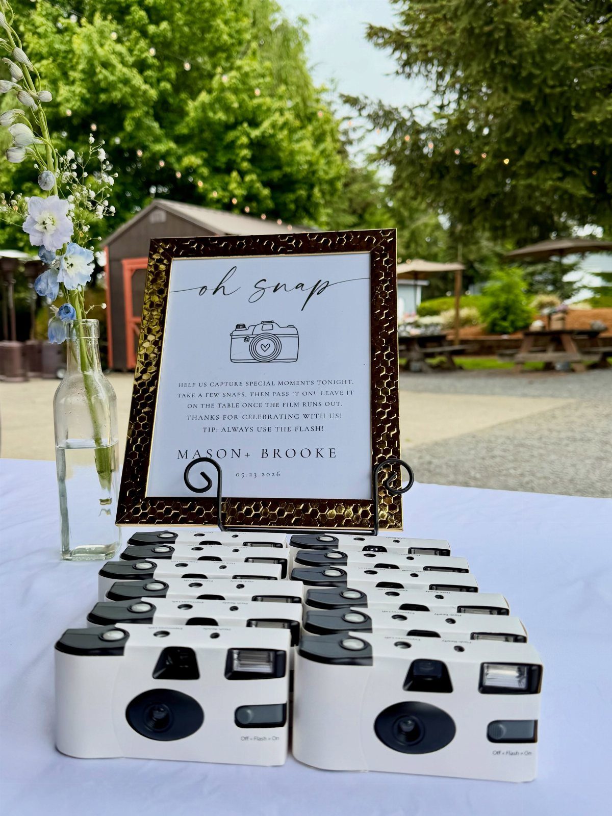 White instant cameras and a framed sign on a wedding guest book table.