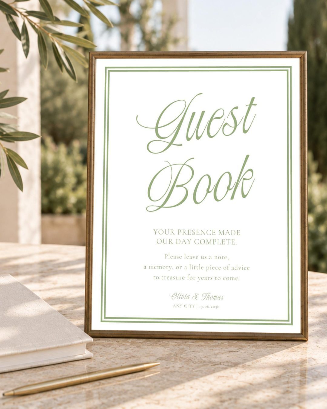 Framed guest book sign on a marble table with a pen and book.
