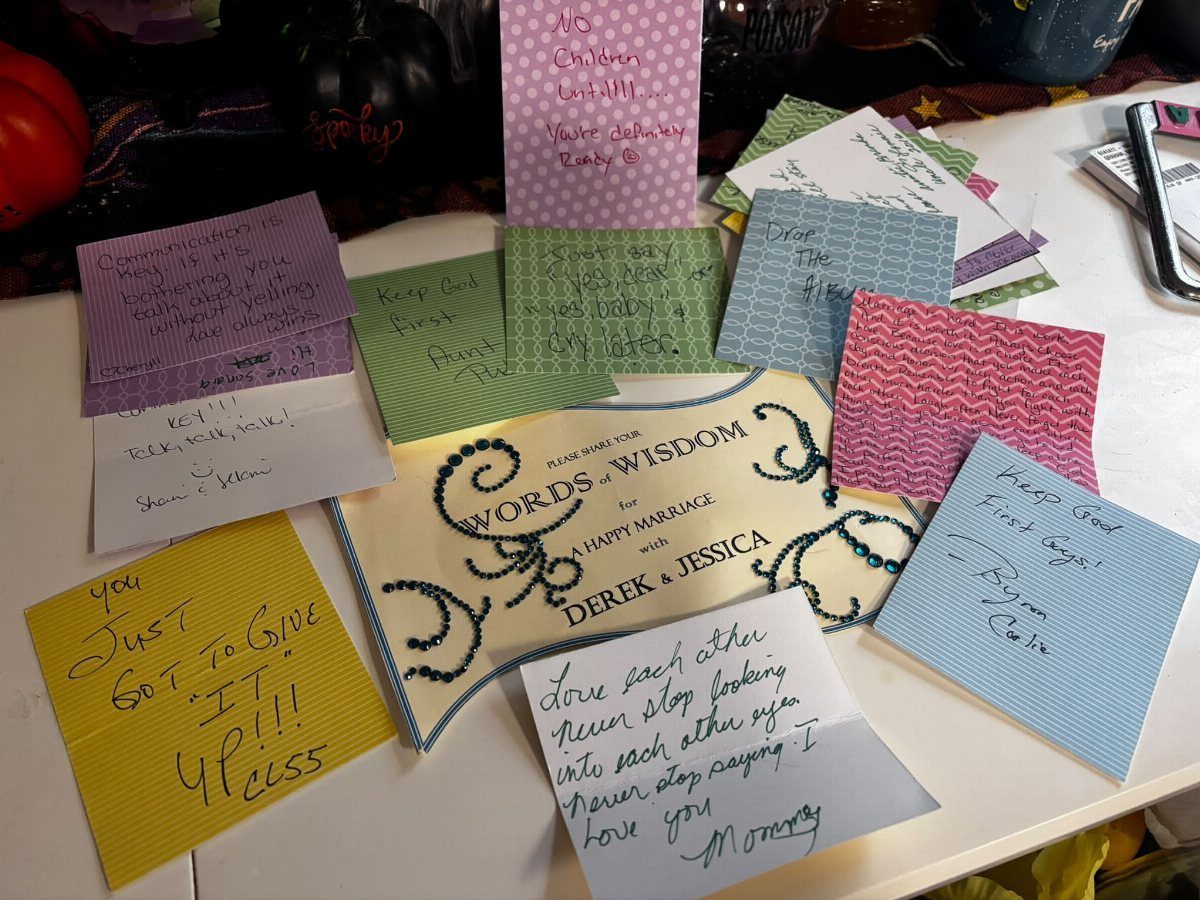 Handwritten advice notes on colorful paper surrounding a Words of Wisdom wedding sign.