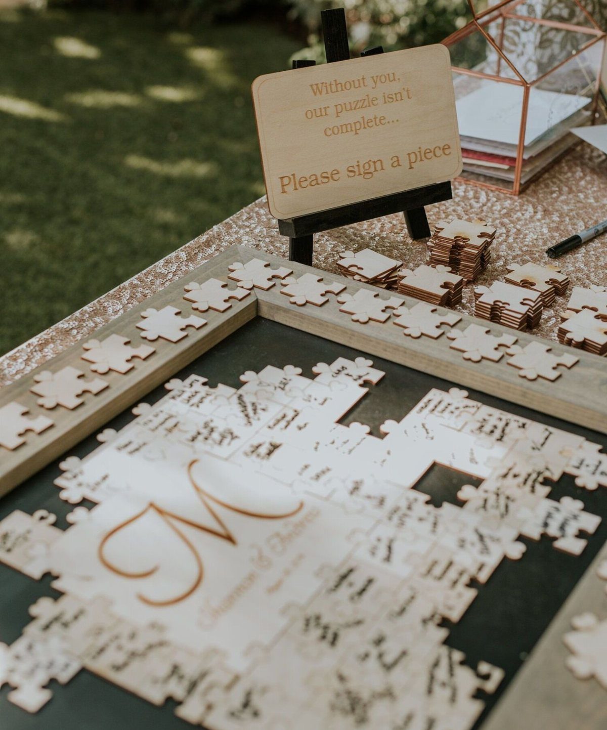 Wooden puzzle guest book with signed pieces and a request sign on a table