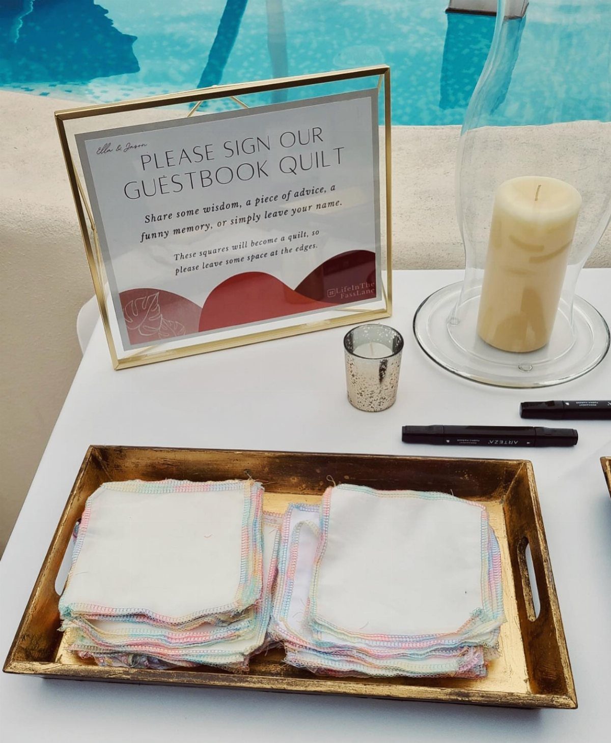 Fabric squares on a gold tray with a sign for a guestbook quilt.