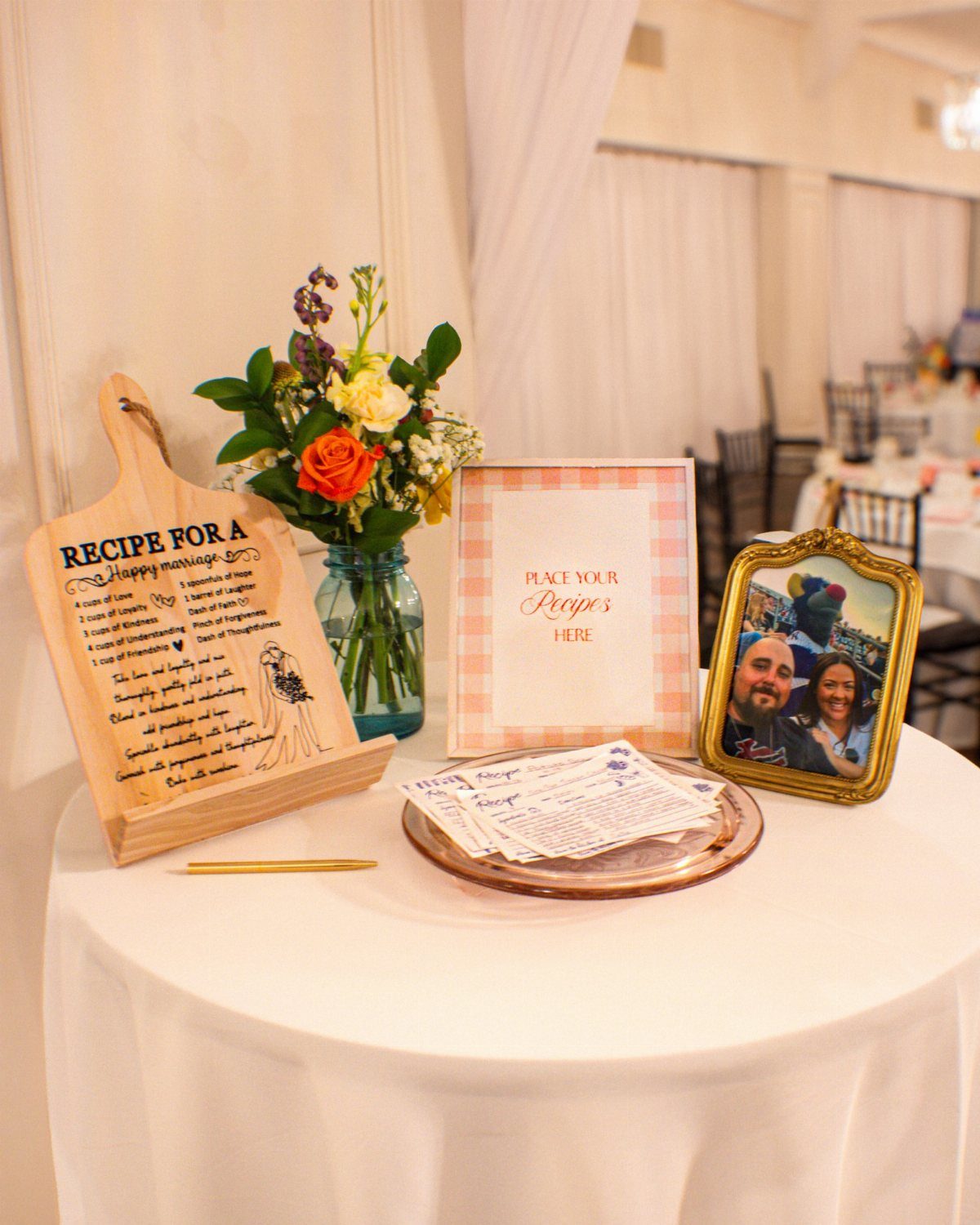 Wedding guest book station with recipe cards, wooden cutting board, and fresh flowers.