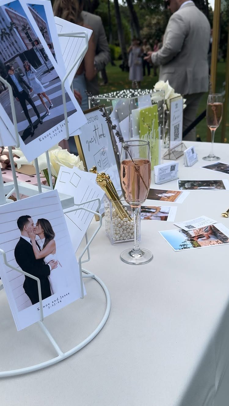Wedding table setup with photo holders, postcards, and a glass of rosé wine.