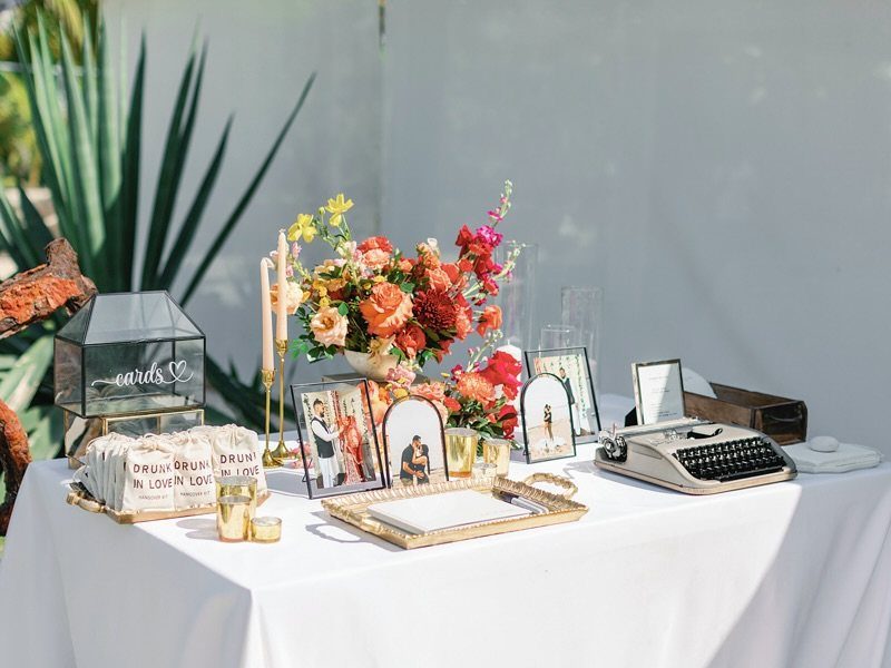 Vintage typewriter and wedding photos on a white table with colorful flowers.
