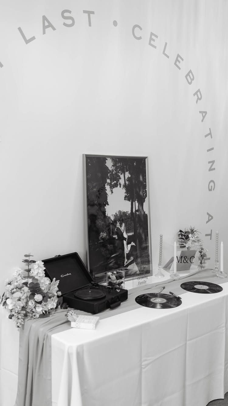 Vinyl records and a record player on a decorated wedding guest book table.