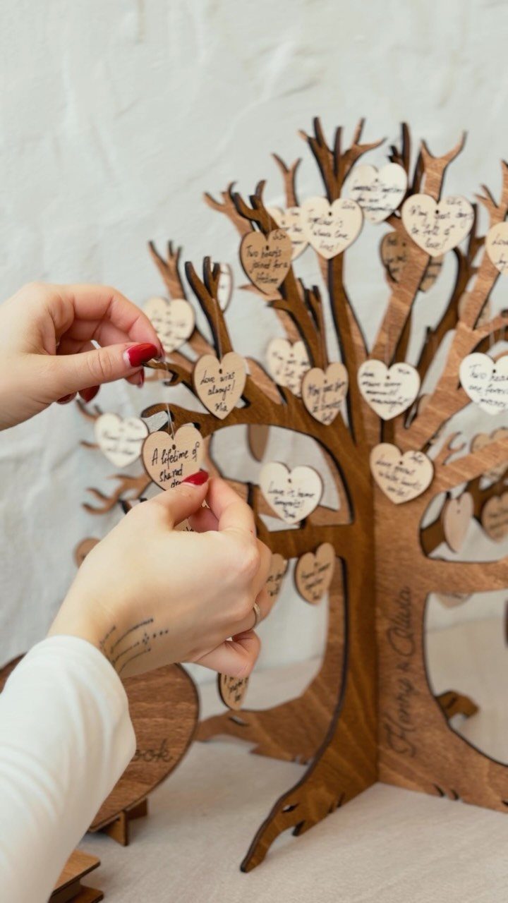 Wooden decorative tree with heart-shaped tags containing handwritten wishes for a wedding.