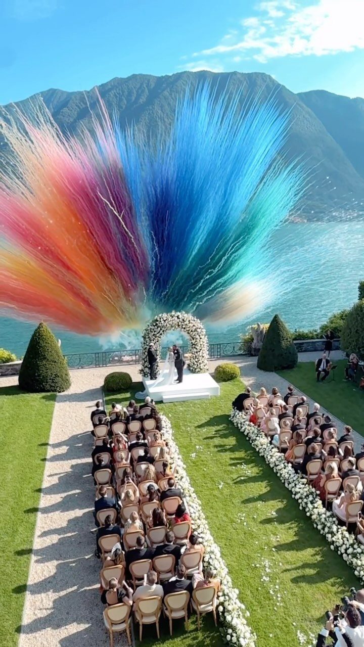 Wedding couple under floral arch with a giant colorful powder explosion behind them.