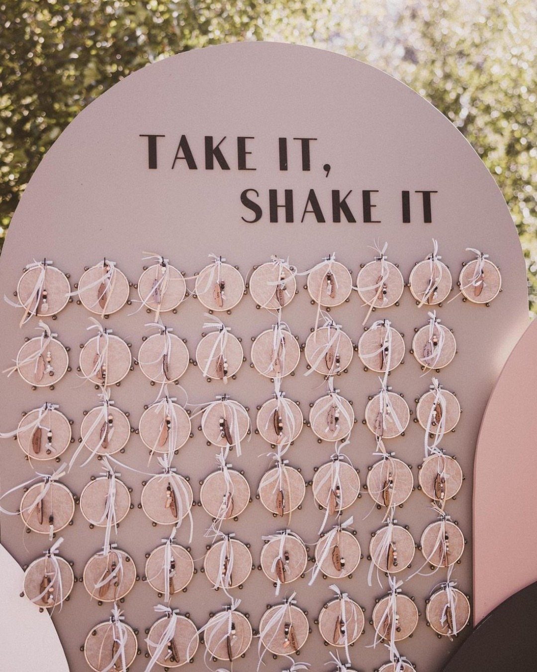 Pink board with gold tambourines and text 'TAKE IT, SHAKE IT' for guests.