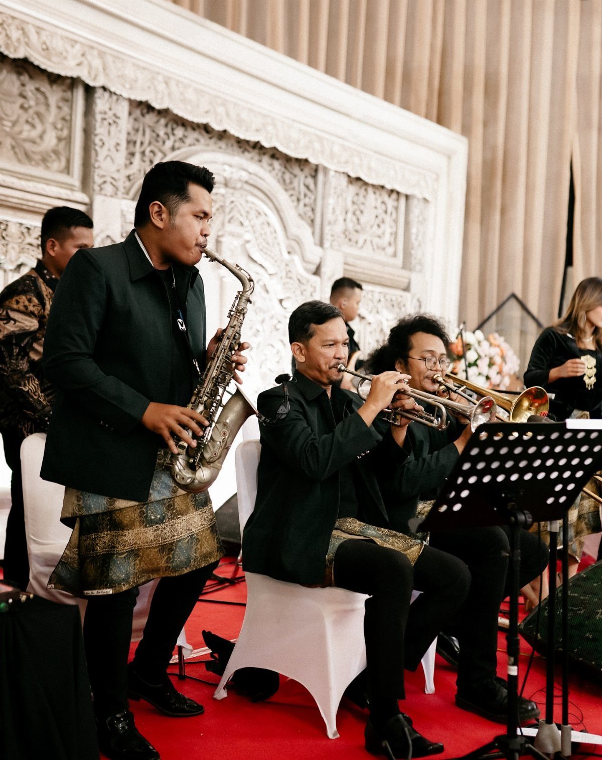 Musicians in traditional attire playing saxophone and trumpets at a wedding event
