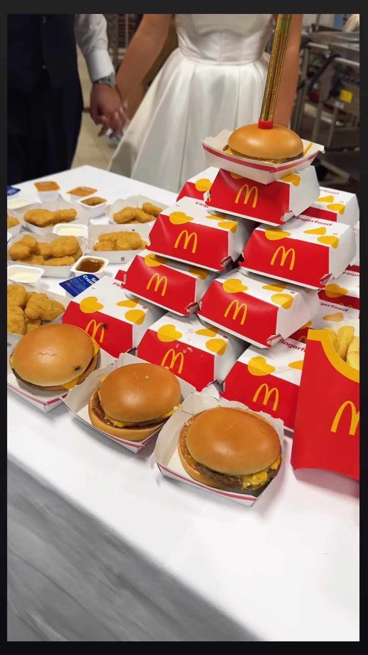 McDonald's burgers and nuggets on a table with a bride and groom behind.