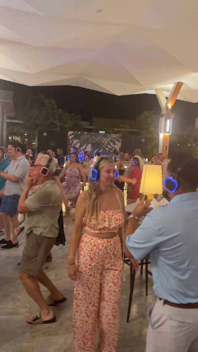 Guests dancing at night wearing glowing blue wireless headphones for a silent disco.