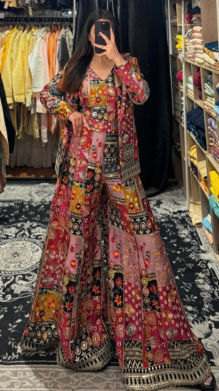 Woman wearing a colorful embroidered pink and gold traditional outfit in a store.