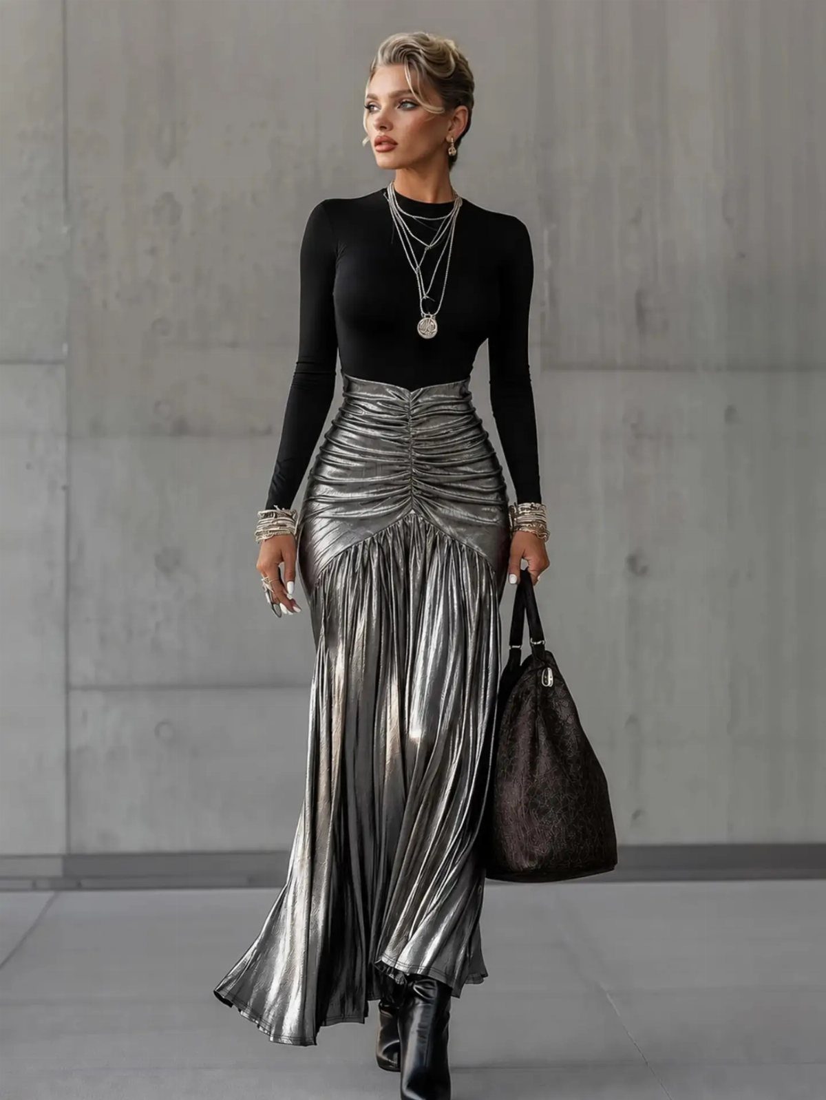 Woman wearing a black knit top and metallic silver pleated maxi skirt with accessories.