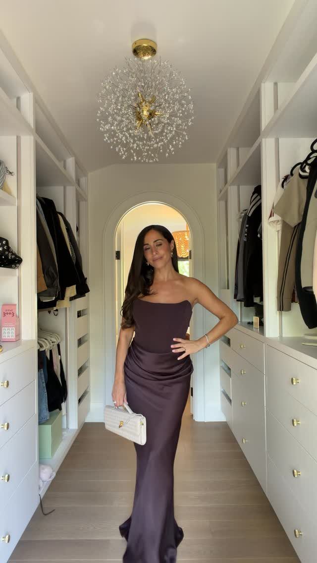 Woman in a strapless purple satin floor-length gown posing in a white closet.