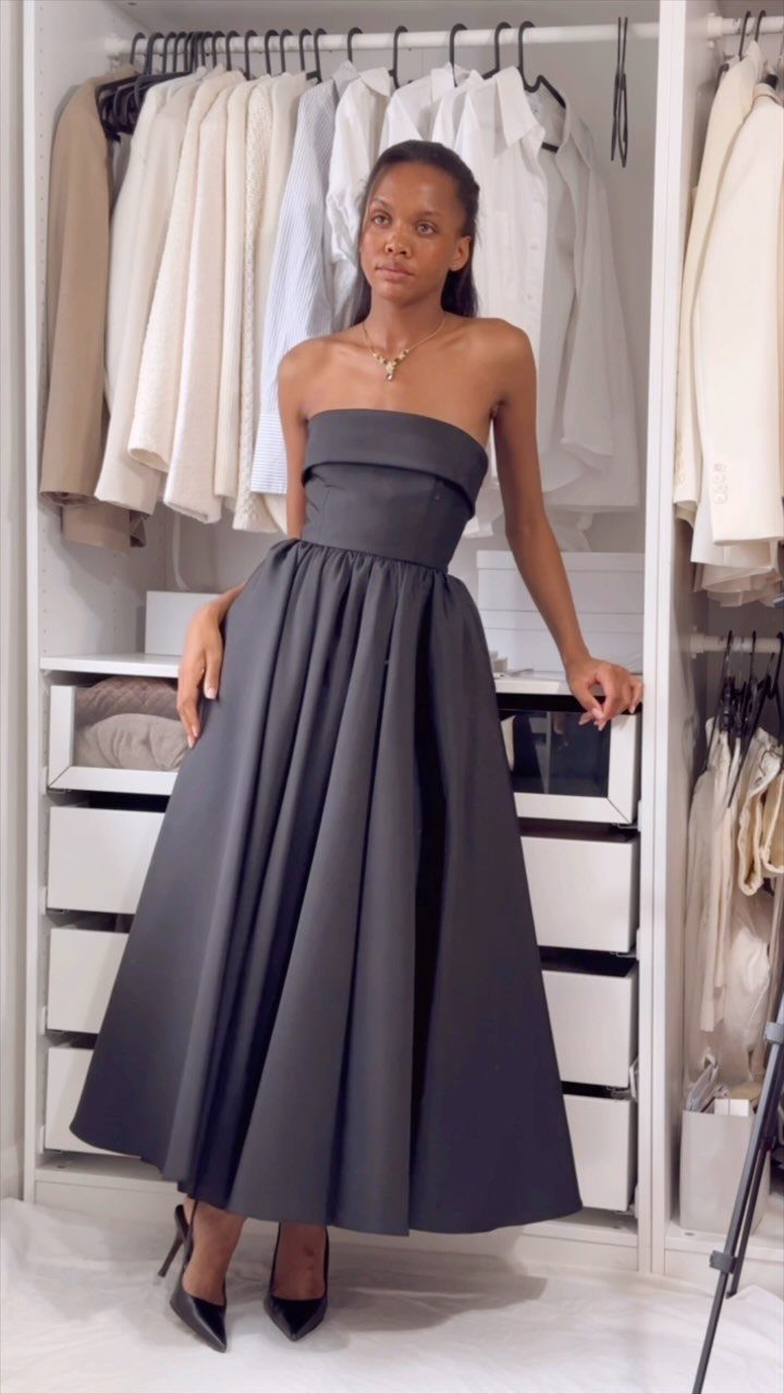 Woman in a strapless black formal gown and heels standing in a white closet