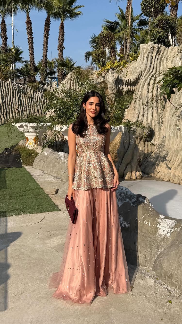 Woman wearing a gold sequined top and rose tulle skirt for a wedding.