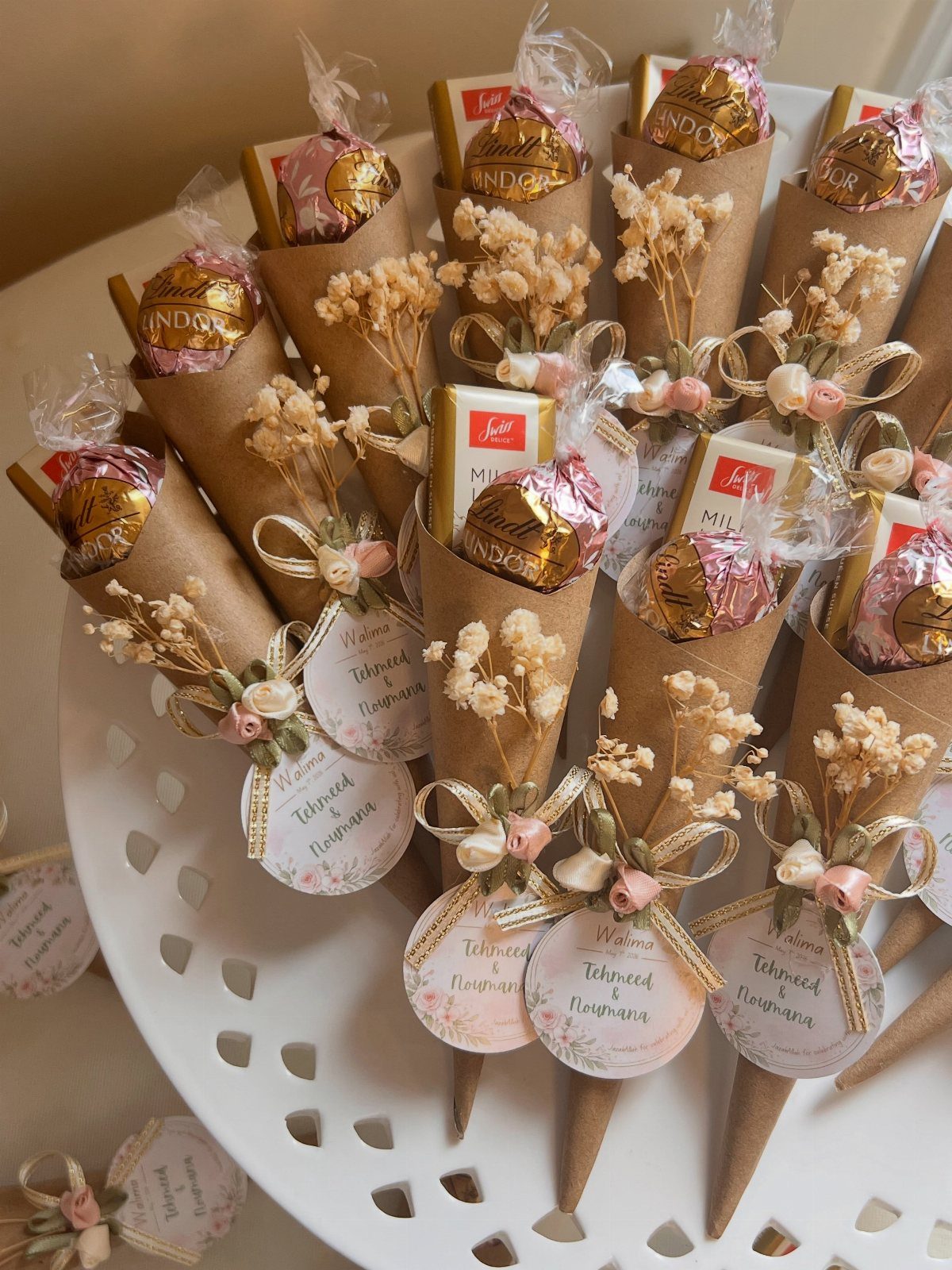 Chocolate treats in brown paper cones with dried flowers and personalized tags.