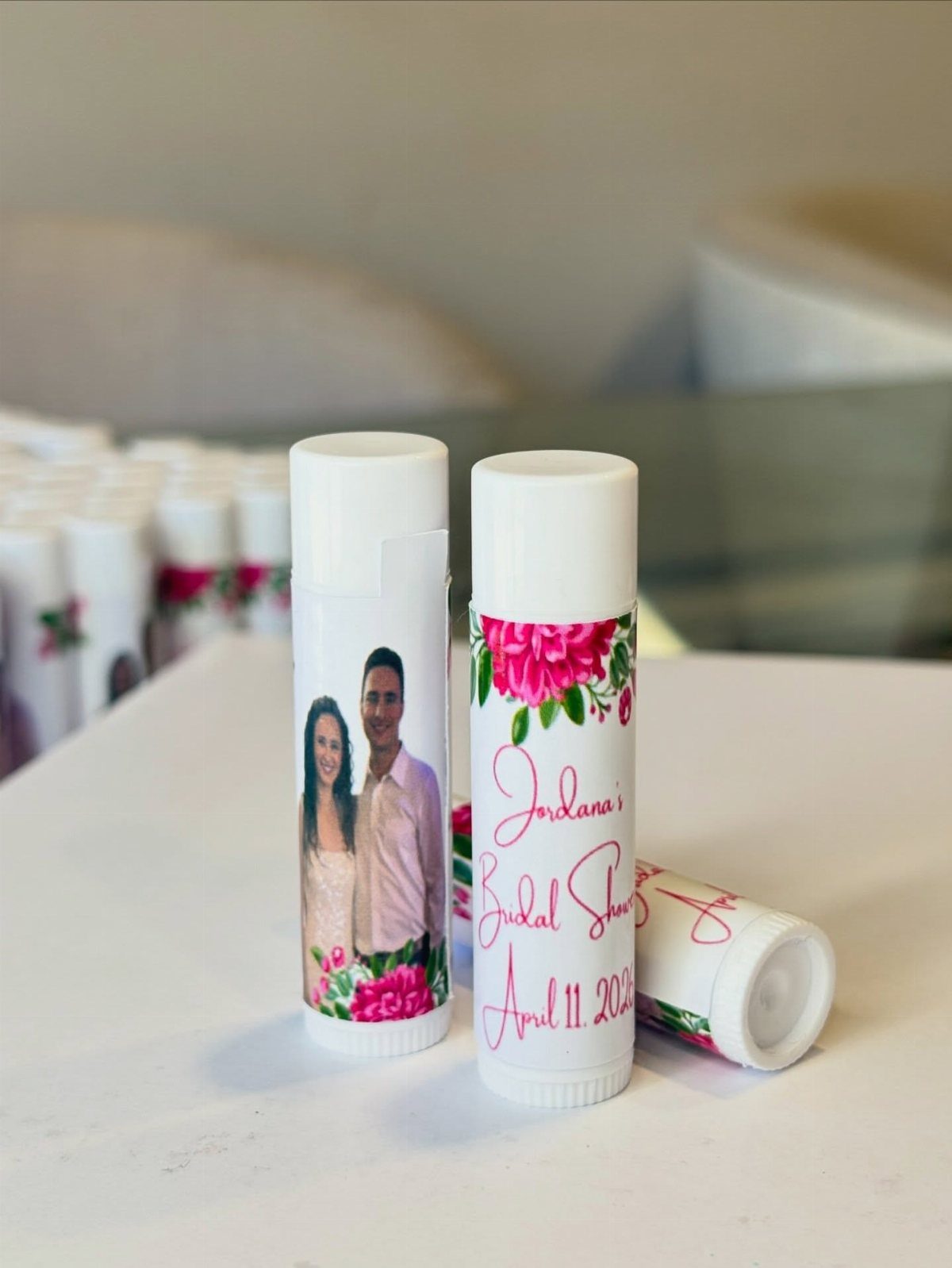 Customized lip balm tubes with a couple's photo and pink floral labels.