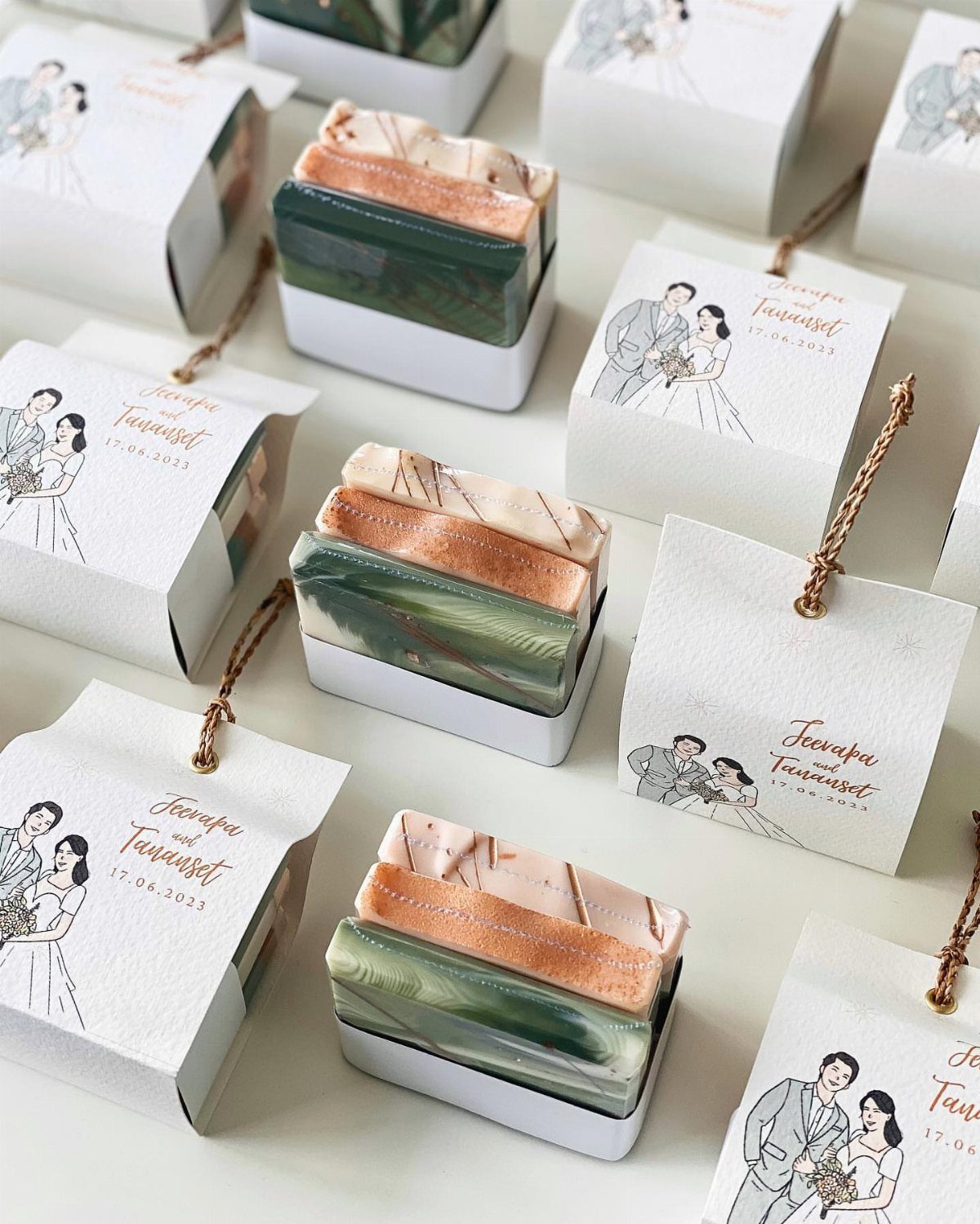 Marbled handmade soap bars in white trays with wedding favor boxes and tags.