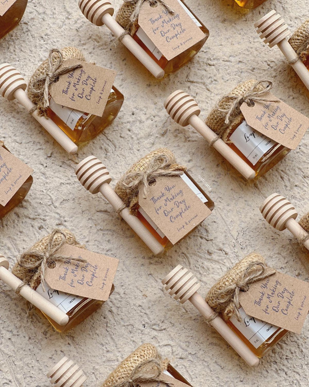 Mini honey jars with burlap lids, wooden dippers, and white gift tags.
