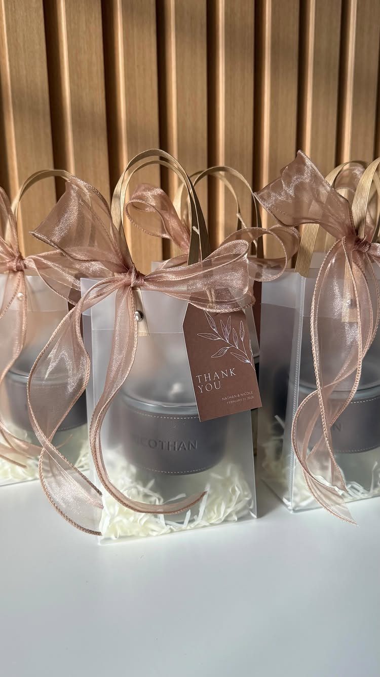Small grey candles in clear gift bags with rose-gold ribbons and thank you tags.