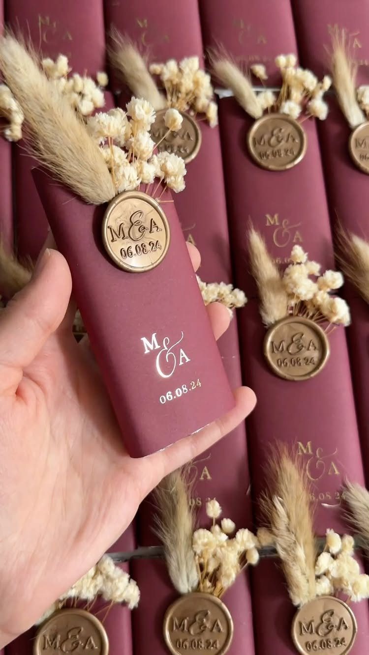 Burgundy envelopes with gold wax seals and dried flowers for wedding guests