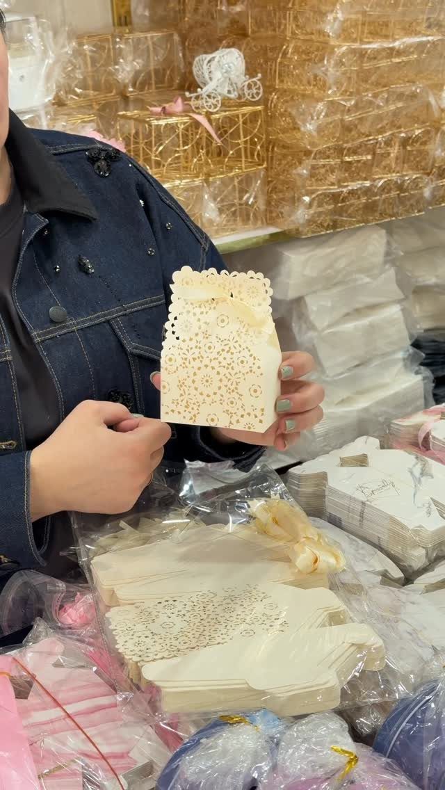 White laser-cut decorative gift box held by a person among other packaging supplies.