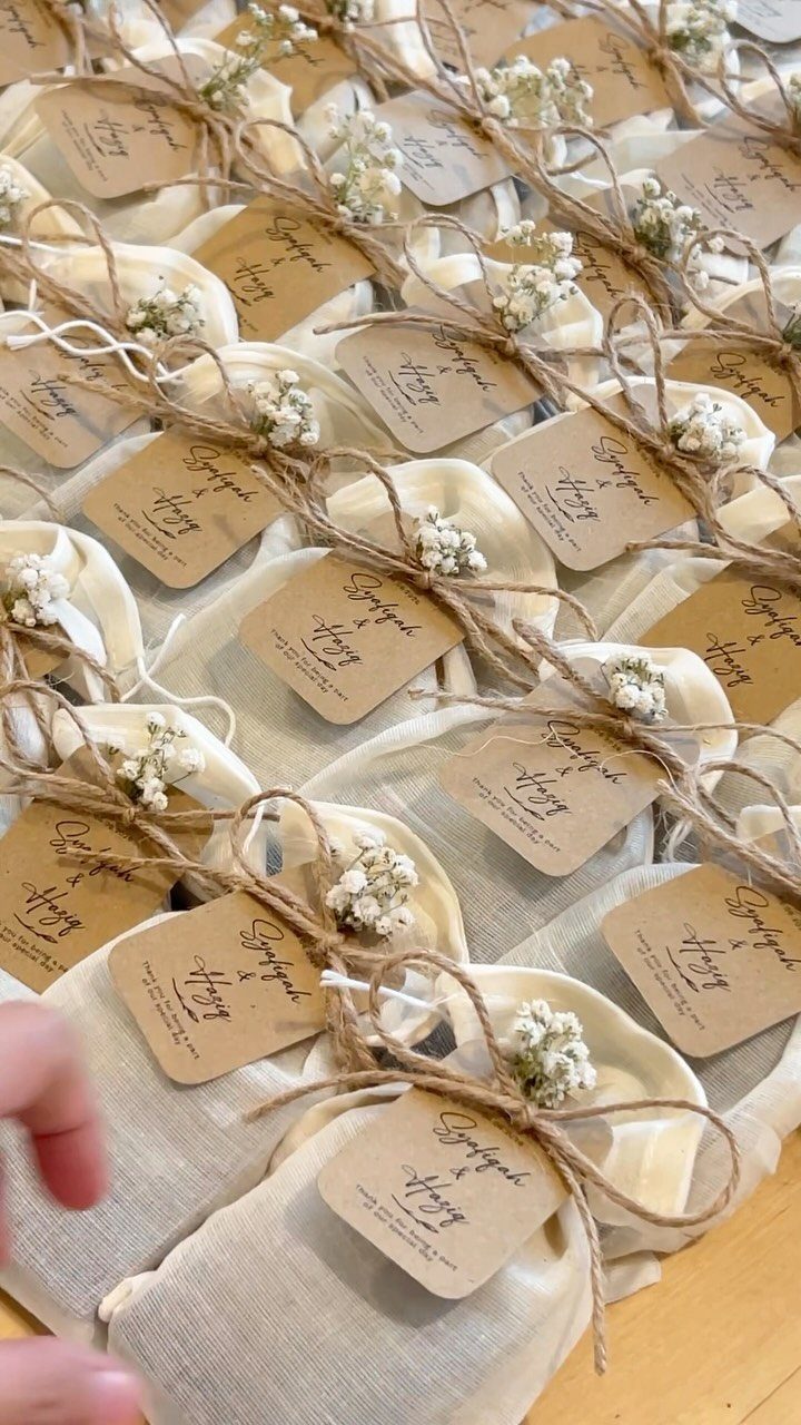 Cream fabric gift pouches tied with twine, baby's breath, and kraft paper tags.