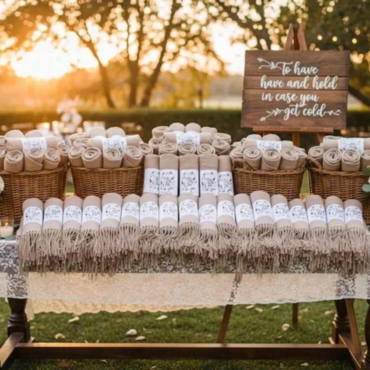 Rolled beige blankets with labels on a lace table for wedding guests.