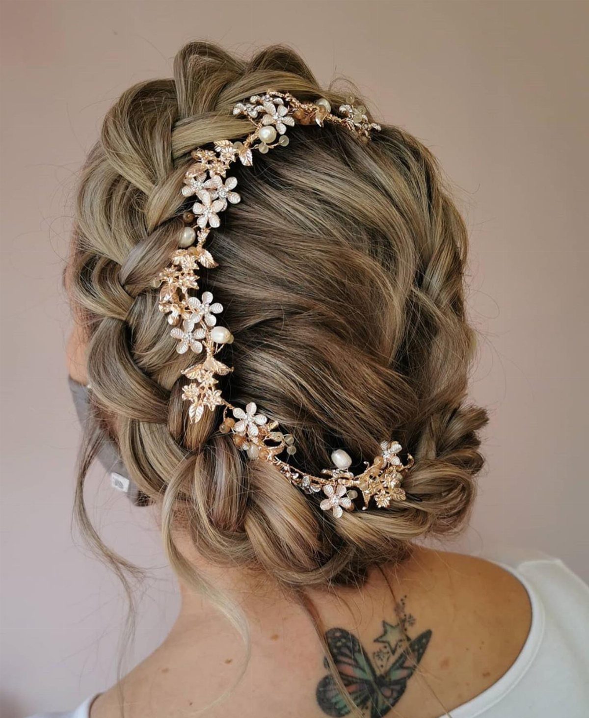 Braided blonde updo with a gold floral and pearl crown hair accessory