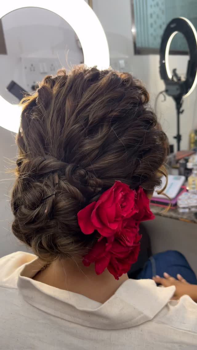 Brown hair styled in a low twisted updo with a large red flower