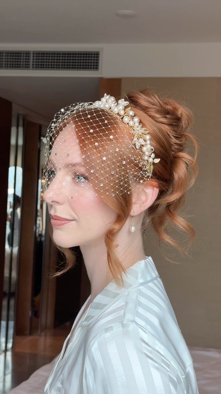 Woman with red hair updo wearing a pearl birdcage veil and headband