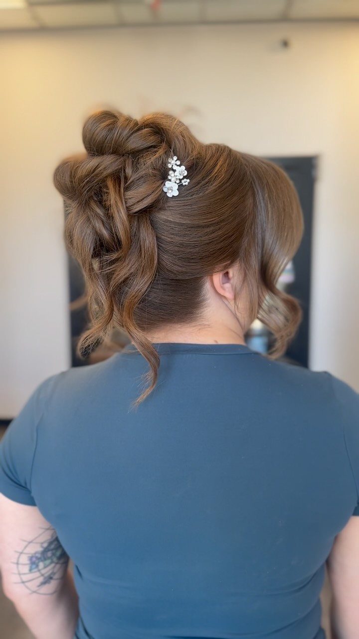 Brown hair styled in a romantic up-do with a small floral hair clip.