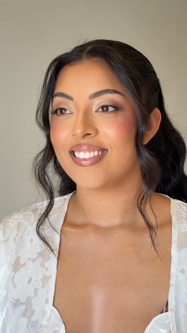 Woman with dark skin wearing bridal makeup and a white floral robe