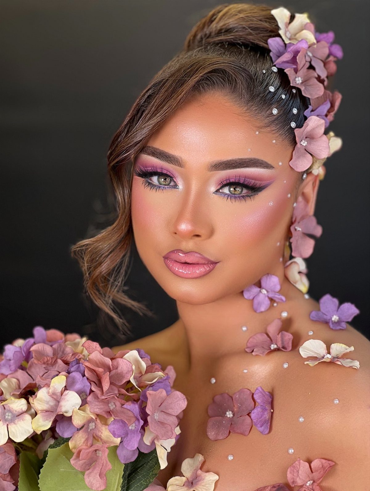 Woman with tan skin wearing bright purple eyeshadow and floral skin adornments