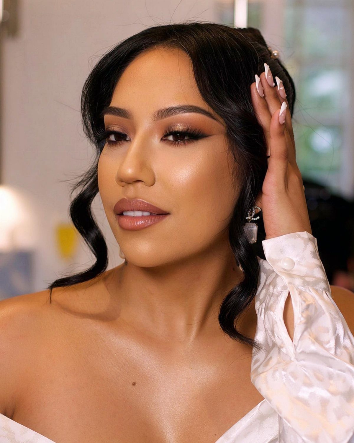 Woman with tan skin wearing subtle yet sultry bridal makeup and white satin dress