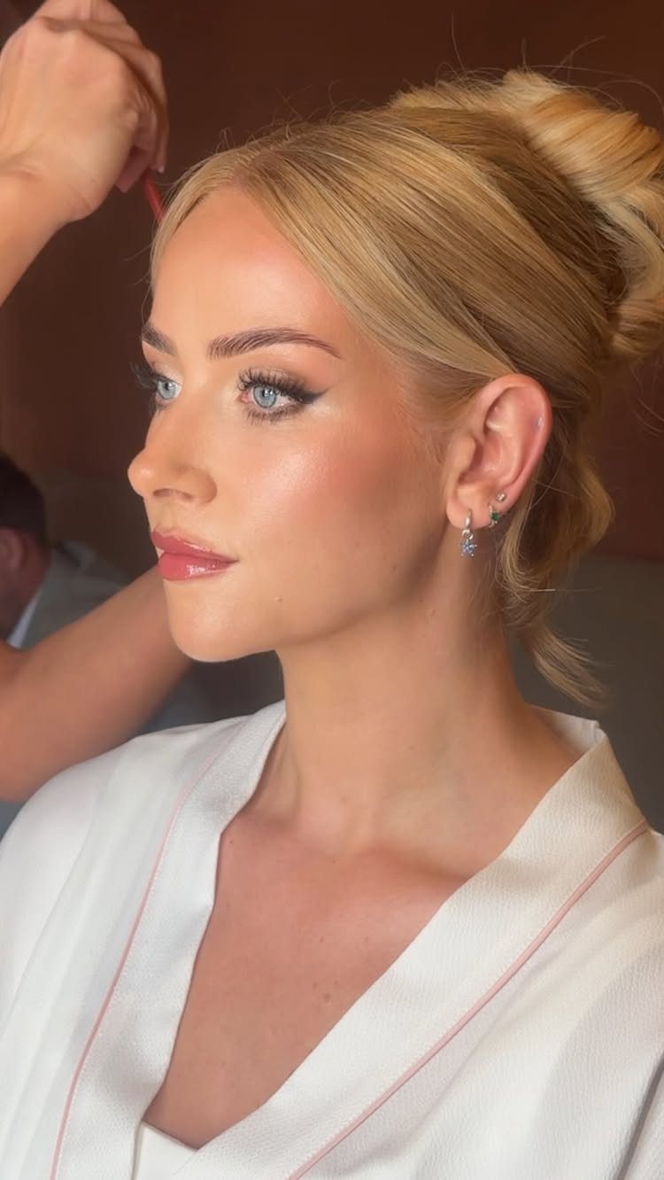 Blonde woman with blue eyes wearing bridal makeup and a white satin robe