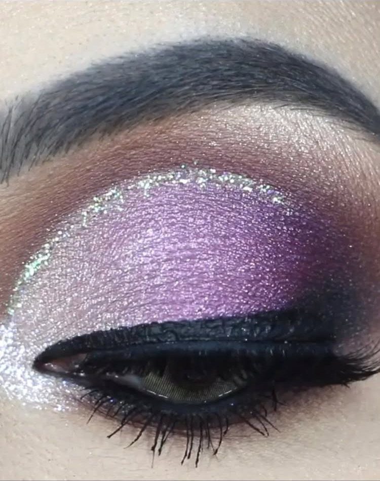 Eye makeup featuring purple and plum eyeshadow with a shimmering silver glitter accent.