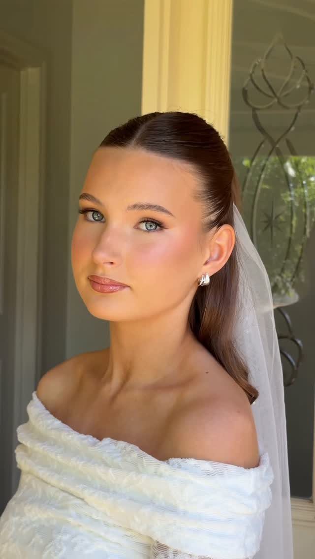 Bride with blue eyes wearing soft glam makeup, white lace dress, and veil.