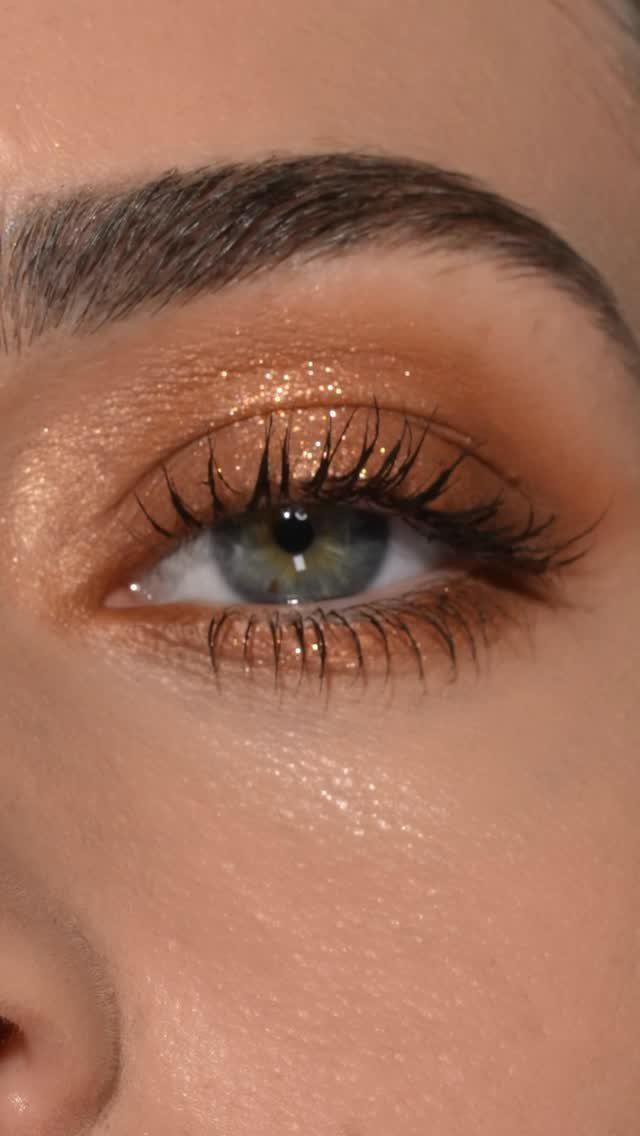Blue eye with shimmering bronze and warm brown eyeshadow and long dark lashes.