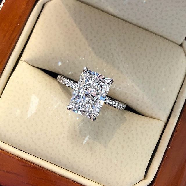 Radiant-cut diamond engagement ring with pavé band in a velvet jewelry box