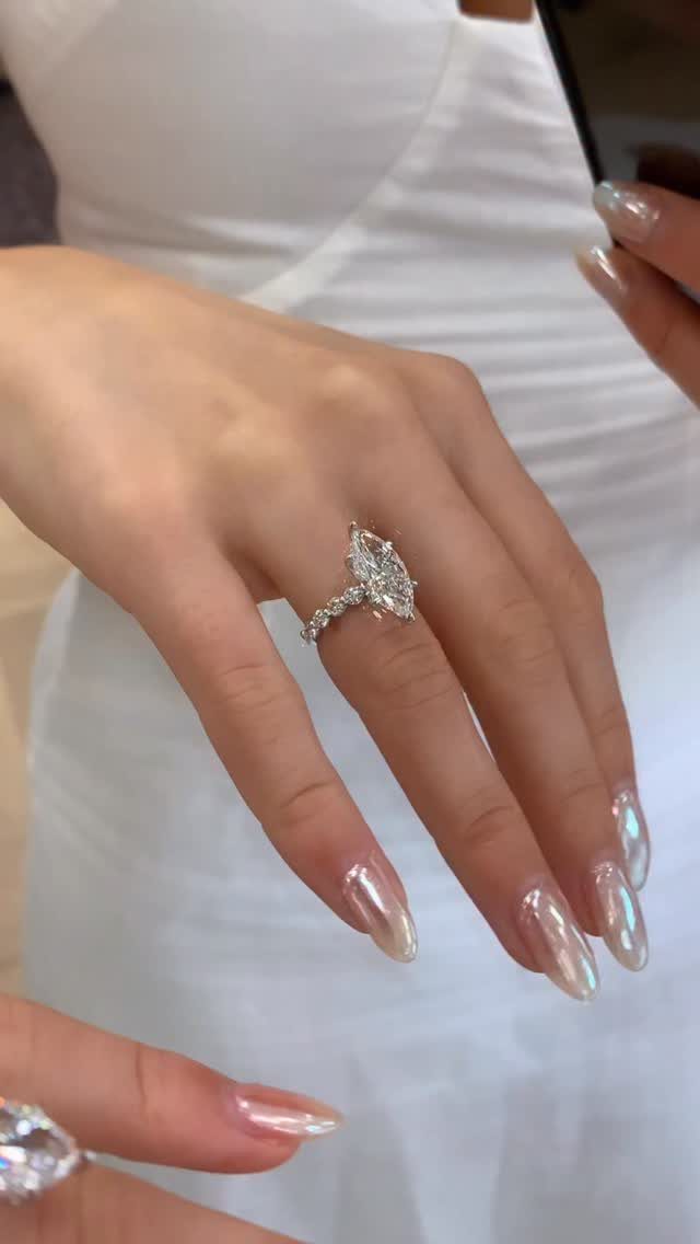 Pear-shaped diamond engagement ring on a hand with iridescent pearlescent nails