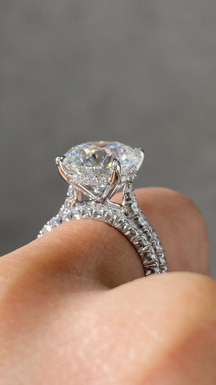 Large round-cut diamond engagement ring with pavé band on a person's finger