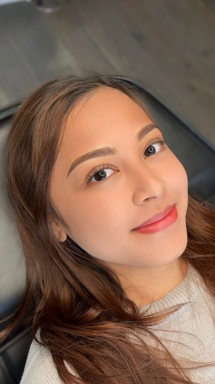 Woman with soft glam makeup and fluffy natural brows looking at camera