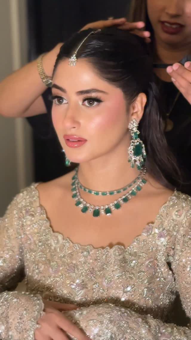 Woman with soft glam makeup wearing emerald jewelry and gold embroidered bridal attire