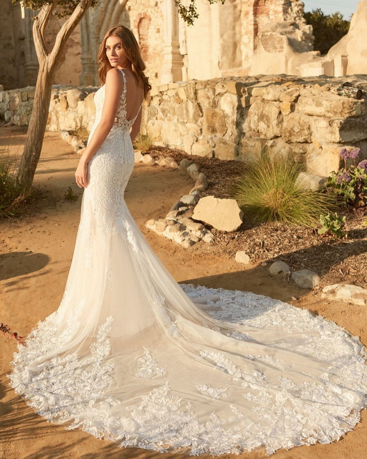 Woman in a white lace mermaid wedding gown with a long floral train.