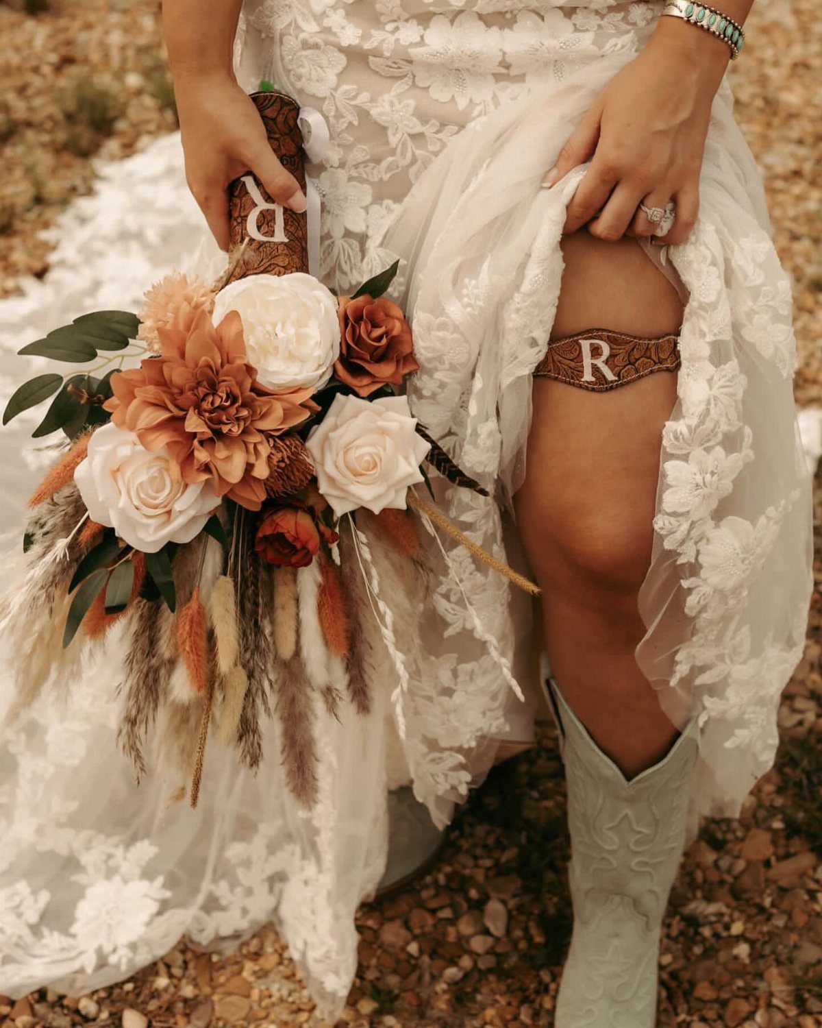 Bride in lace wedding dress and cowboy boots holding an autumn floral bouquet