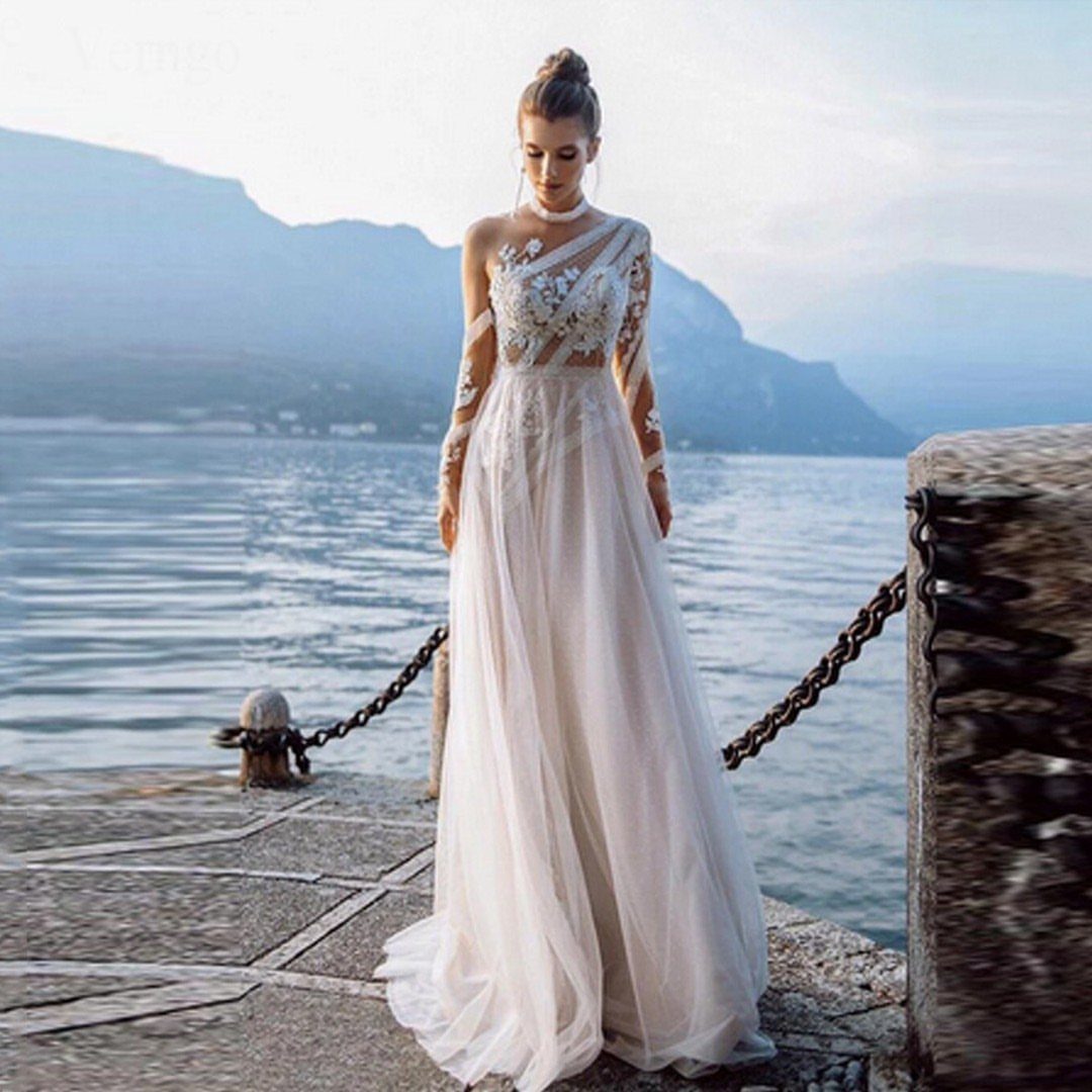 Woman in a white lace boho wedding dress with long sleeves on a pier.