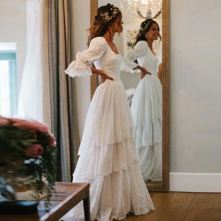 Woman in a white tiered boho wedding dress with bell sleeves and floral crown.